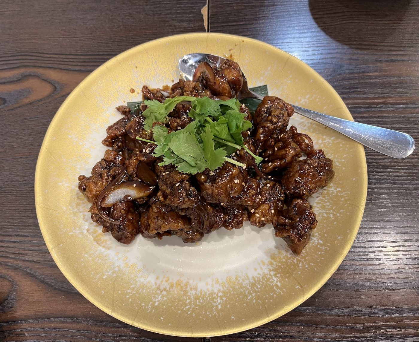 Crisp-fried pieces in a dark caramel glaze with sesame seeds, sliced onion and coriander